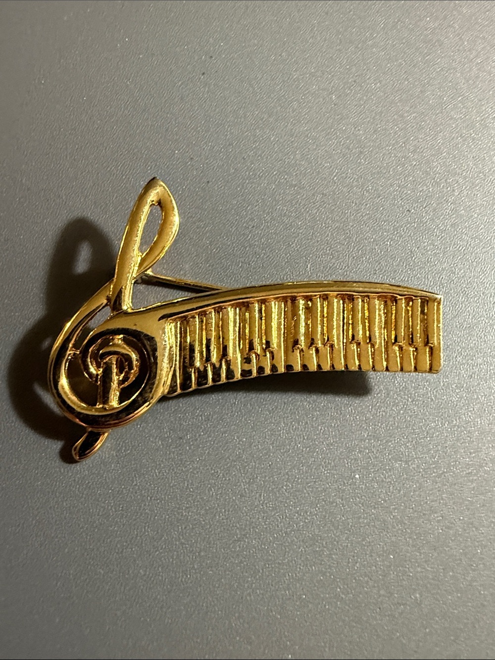 vintage brooch features a gold-toned 3D treble clef & piano keyboard design.